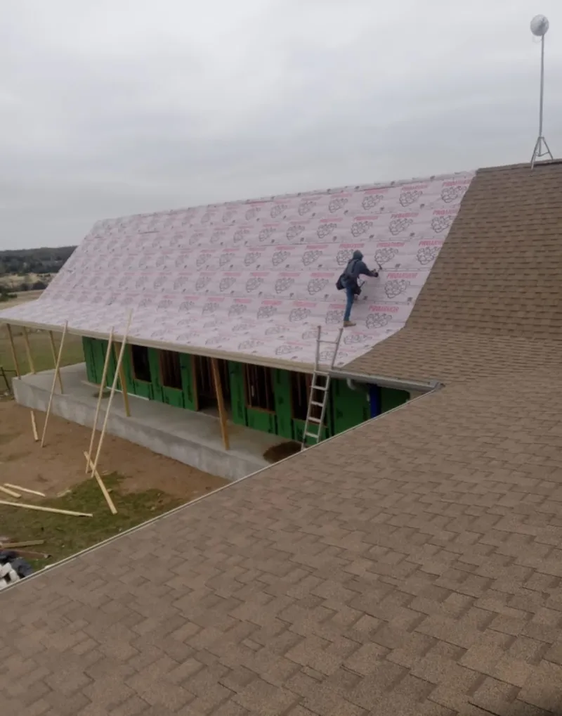 Worker preparing underlayment for a metal roof installation in Marple